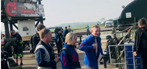 Two of the team walk towards the plane accompanied by a parachute instructor.